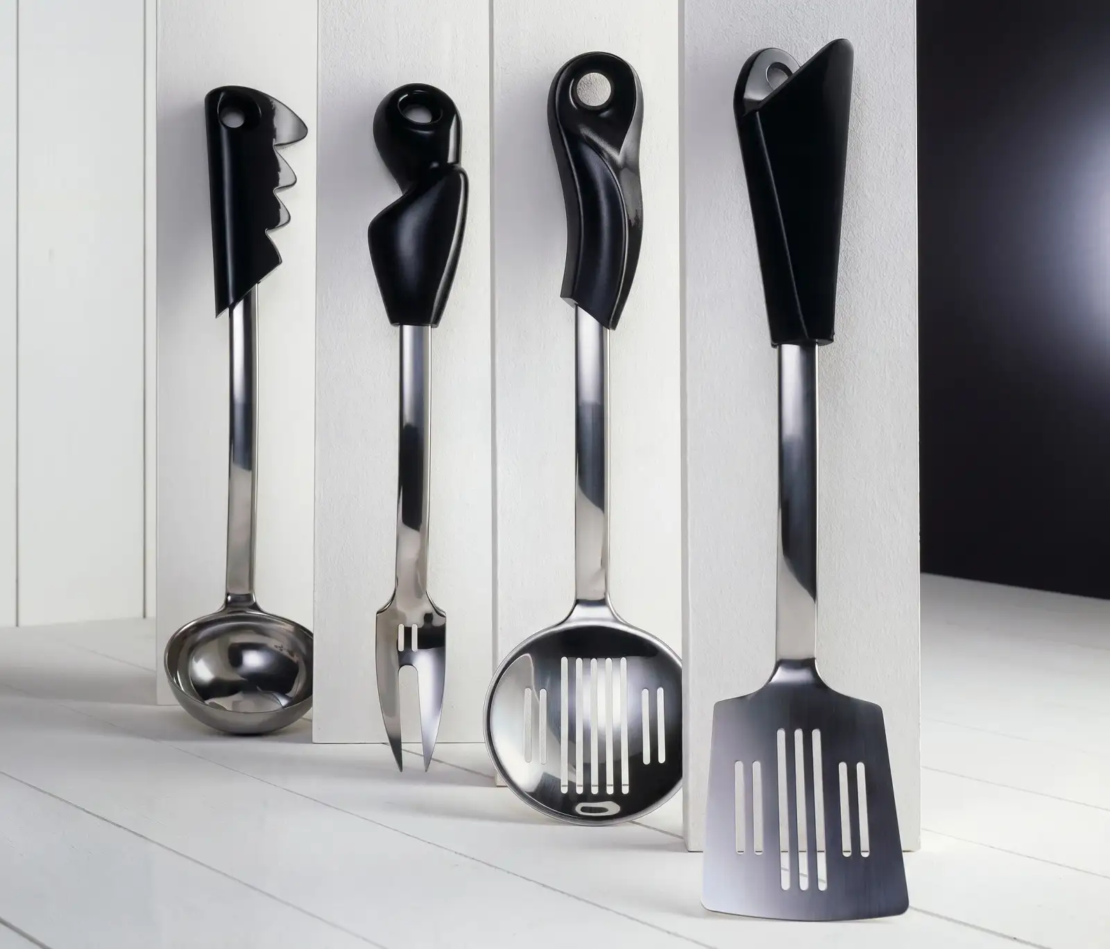 Quattro utensili da cucina in acciaio con manico nero della serie Atelier 75, Fratelli Guzzini