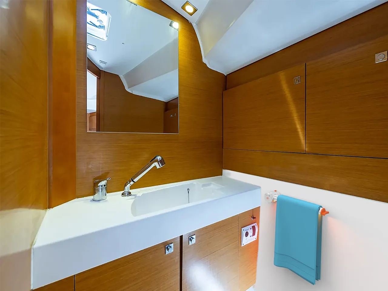 Lo scaldasalviette con una salvietta azzurra nel bagno di una barca, accanto al lavabo, fra pareti rivestite in legno