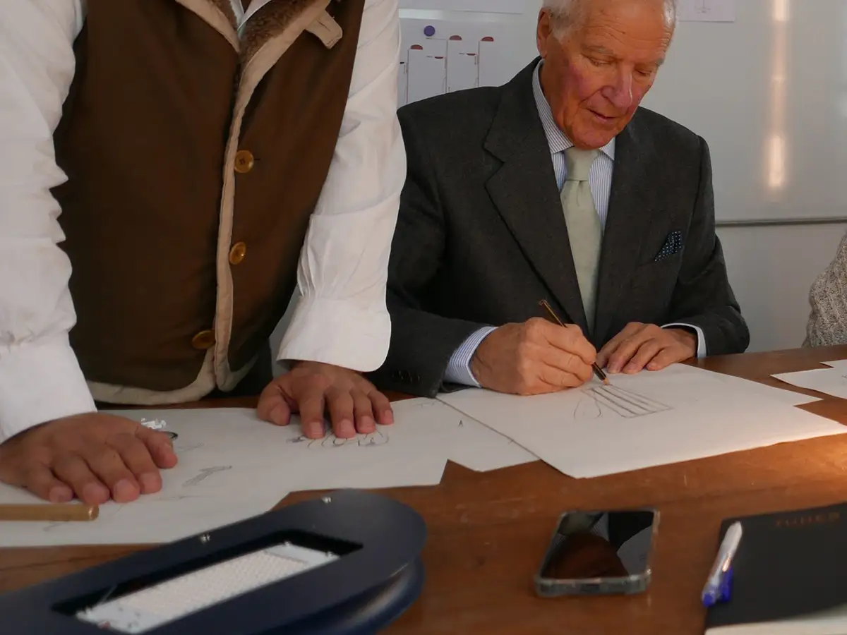 Bruno Gecchelin firma un disegno al tavolo di lavoro, accanto ai moduli LED della riedizione