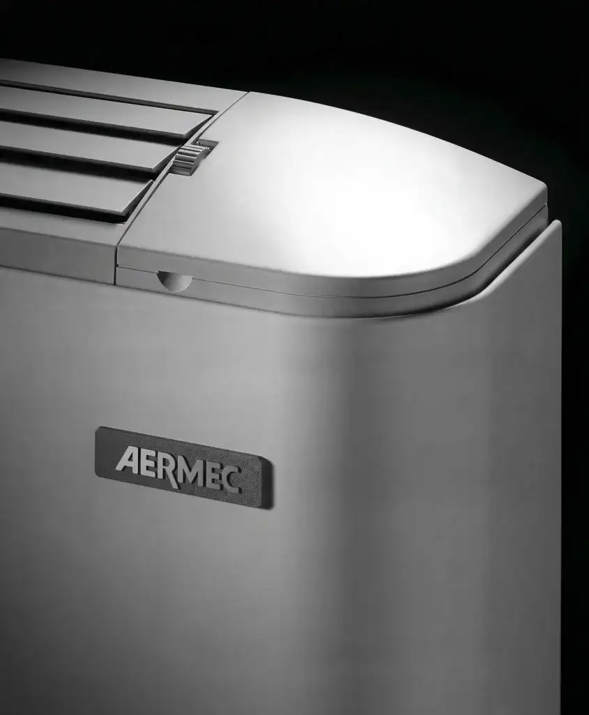 Dettaglio dell’angolo arrotondato del ventilconvettore Omnia con griglia superiore e marchio Aermec, Aermec