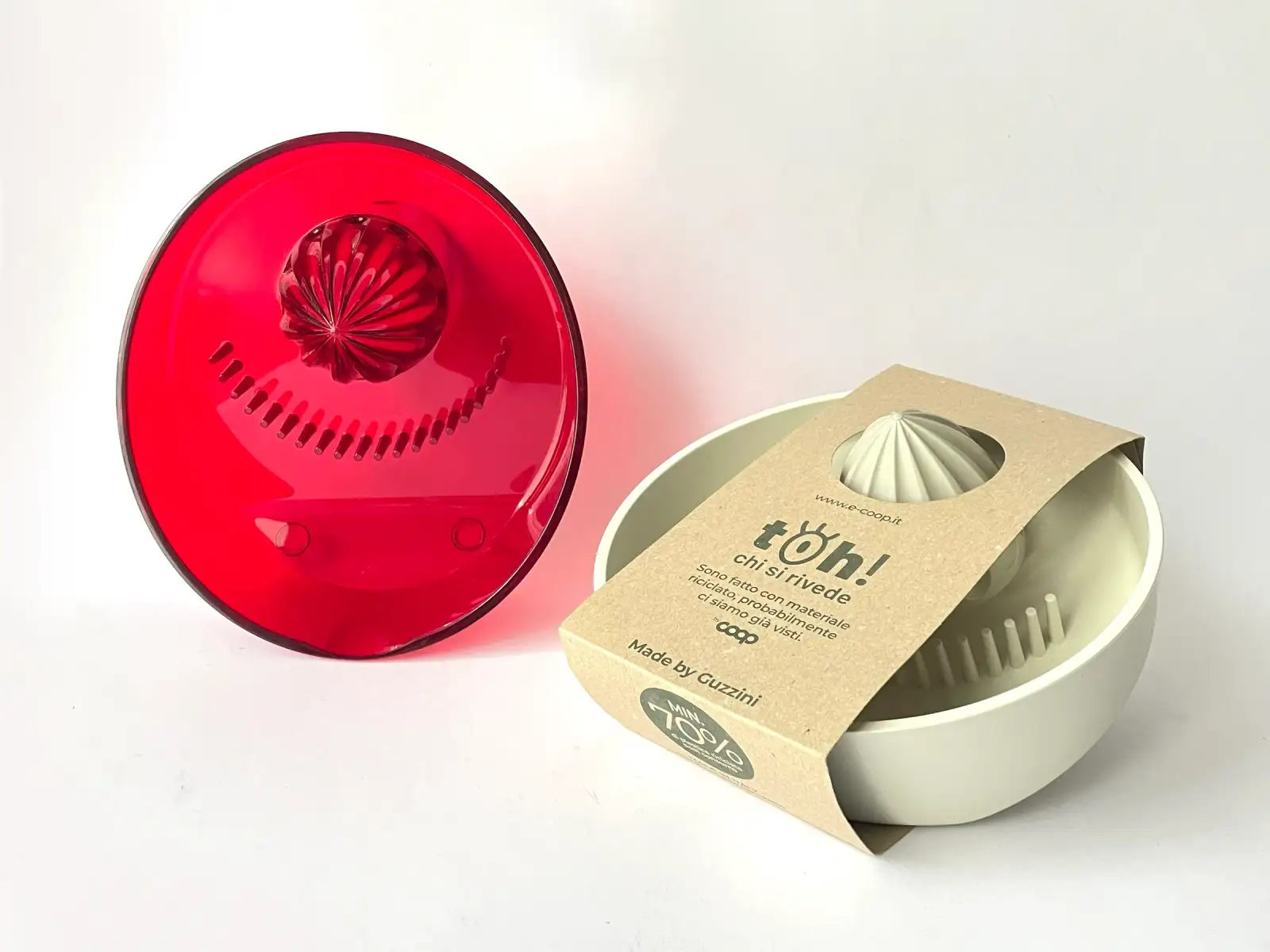 Spremiagrumi LaTina rosso trasparente accanto alla versione in materiale sostenibile con la sua confezione, Fratelli Guzzini