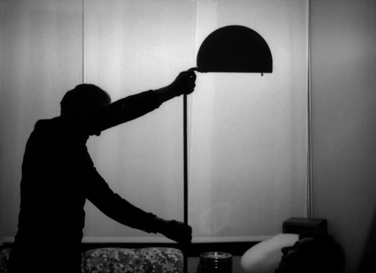 Fotografia storica in bianco e nero: una persona afferra la testa della lampada per orientarla