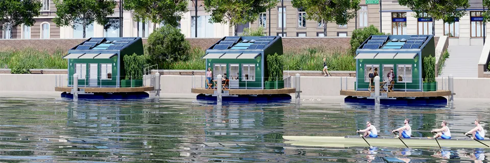 Tre case galleggianti lungo la riva di un fiume in città, con un equipaggio di canottaggio in primo piano